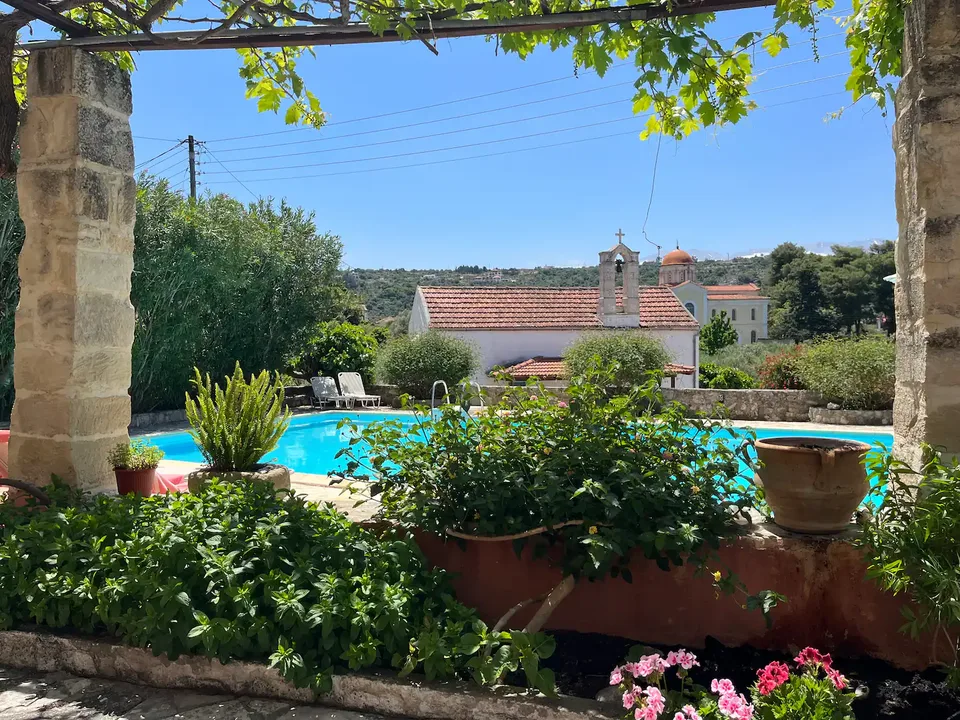 Uitzicht vanaf de tafel op het terras op het zwembad en de kapel — Spiti Athinà, Gavalochori, Kreta