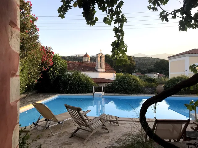Uitzicht vanaf het terras op het zwembad, de kapel, de kerk en de olijfbomen — Spiti Athinà, Gavalochori, Kreta
